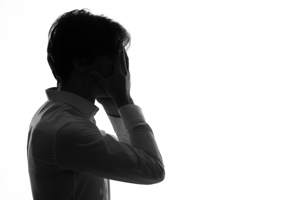 male person silhouette looking stressed with hands around his face white background